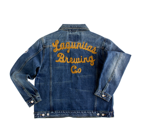 “A premium quality jacket with a stylish denim design. This classic trucker jacket is crafted for women and features Lagunitas patches for added detail. The comfortable and durable fabric makes it a versatile outerwear option, perfect for casual wear and layering. With a button-up closure and stylish pockets, this jacket offers a feminine silhouette and represents Lagunitas with style. Stand out with this fashionable and versatile denim jacket.”